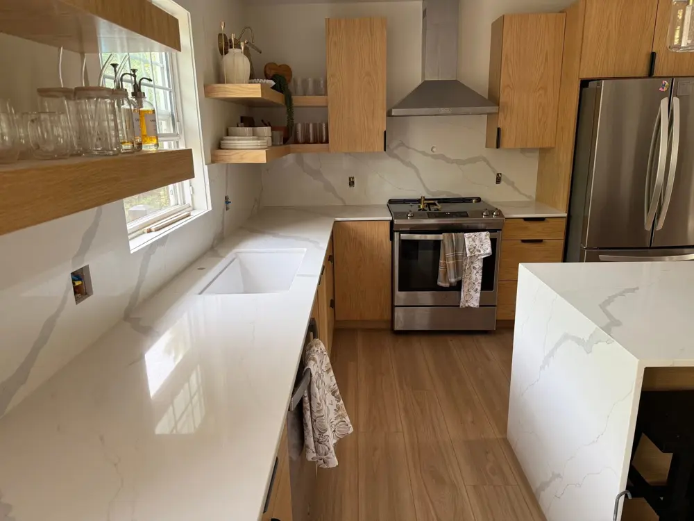 Perimeter countertop with undermount sink beside a waterfall island